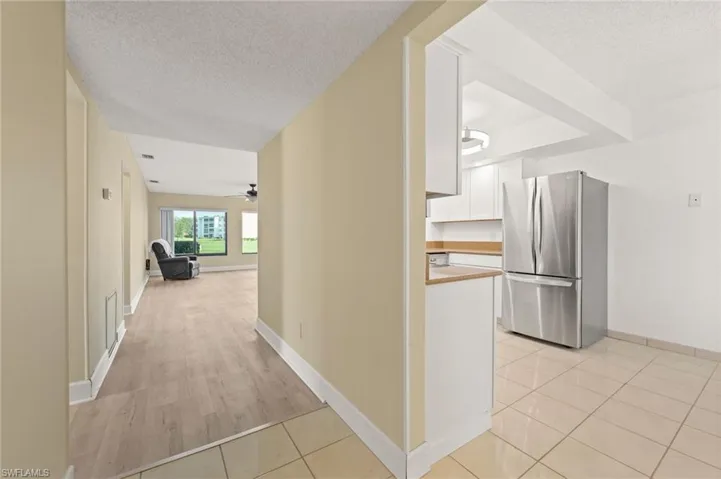 Expansive kitchen featuring white cabinetry, light wood-finish countertops, and a stainless steel refrigerator
