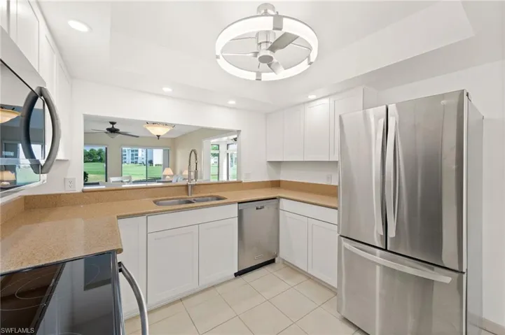 Modern kitchen featuring stone countertops, white cabinetry, stainless steel appliances, and tile flooring
