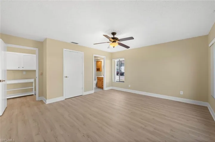 Spacious room featuring wood-finish flooring, neutral-toned walls, and white baseboards