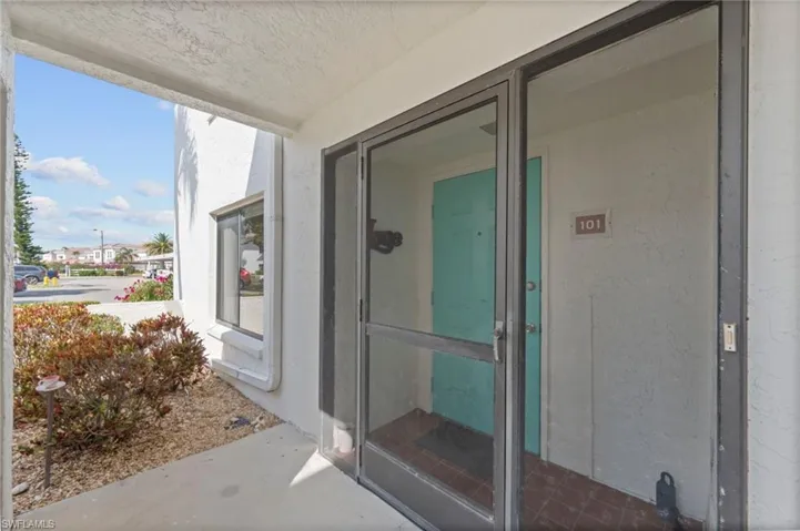 Entryway featuring a screen door, a turquoise-painted door with a house number, and a front window