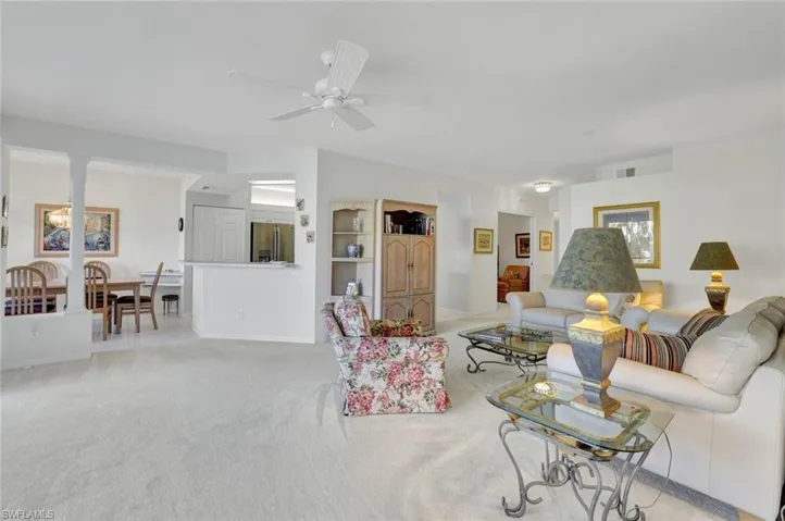 Living room with carpet flooring, ornate columns, and a ceiling fan