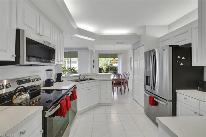 Kitchen with appliances with stainless steel finishes, light countertops, a peninsula, and light tile patterned floors