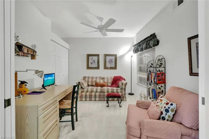 Home office with light colored carpet and a ceiling fan