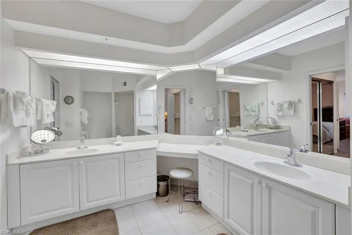 Bathroom featuring two vanities, light tile patterned floors, and a shower stall