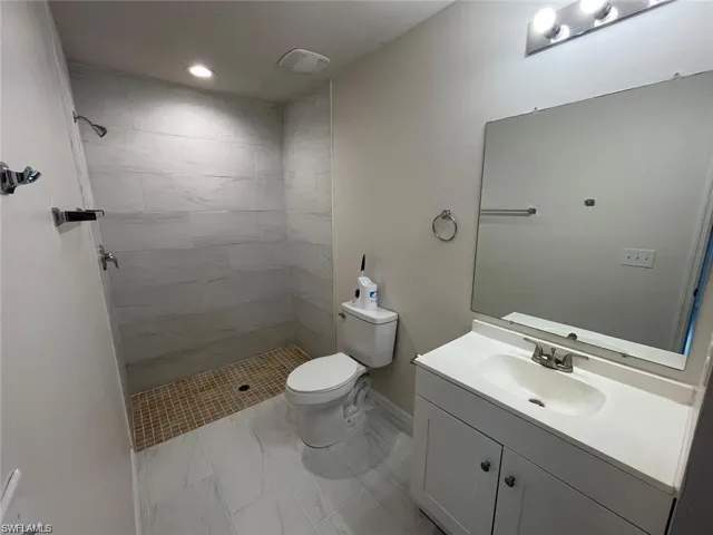 Bathroom with toilet, vanity, and a tile shower