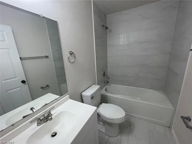 Full bathroom featuring tiled shower / bath, toilet, and vanity