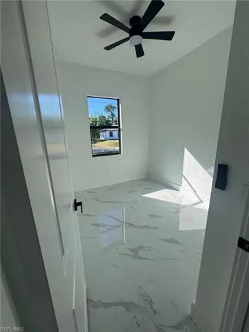 Empty room featuring light marble finish floors and a ceiling fan