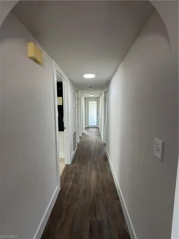 Hallway featuring baseboards and dark wood-style floors