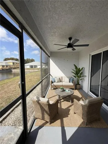 Sunroom featuring outdoor seating, a ceiling fan, and a water view