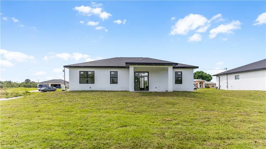Back of house with a yard and stucco siding