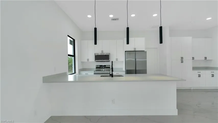 Kitchen featuring a sink, stainless steel appliances, marble finish floor, and light countertops