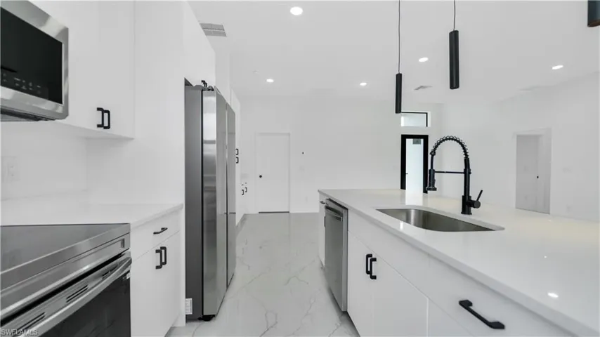 Kitchen featuring visible vents, a sink, stainless steel appliances, light countertops, and marble finish floor