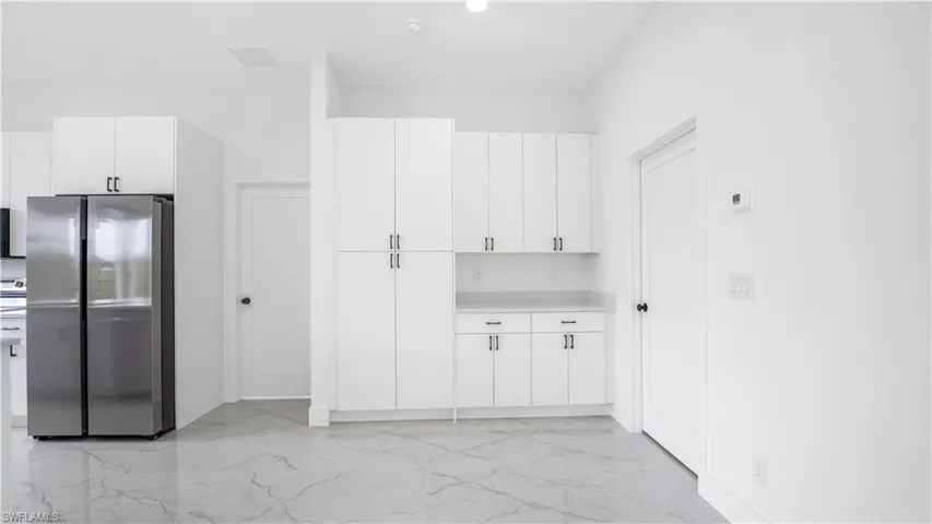 Kitchen with visible vents, light countertops, marble finish floor, and white cabinetry