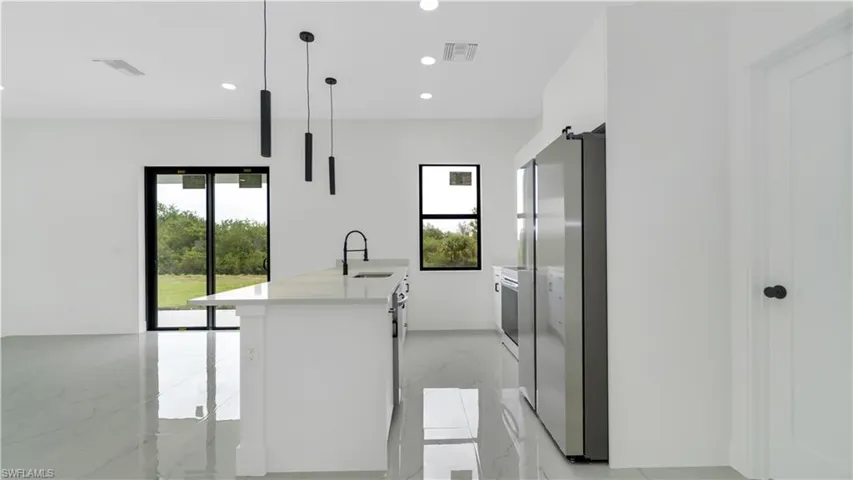 Kitchen with marble finish floor, freestanding refrigerator, a healthy amount of sunlight, and a sink