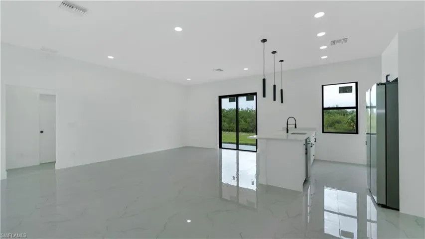 Dining and living room with recessed lighting, visible vents, marble finish floor, and a sink