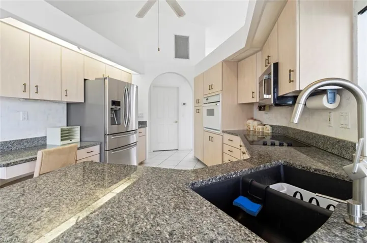 Living area with carpet, high vaulted ceiling, and ceiling fan