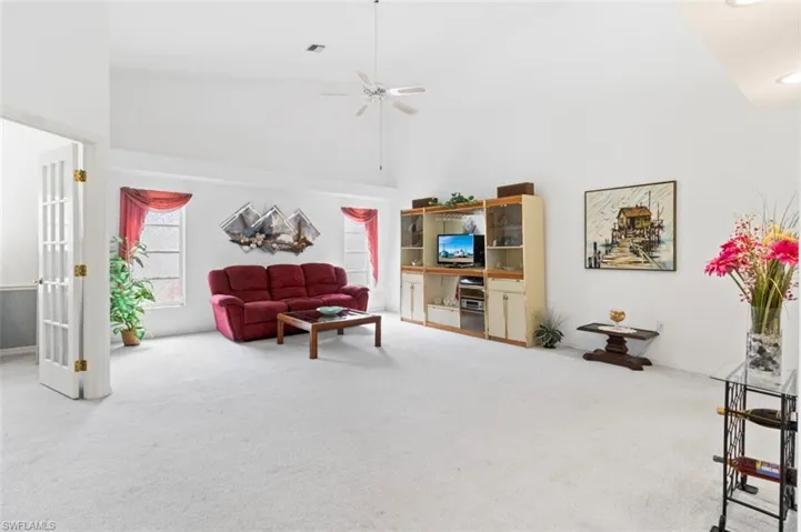 Living area featuring carpet floors, high vaulted ceiling, and a ceiling fan