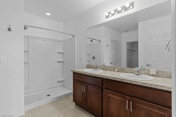 Bathroom featuring tile patterned flooring, vanity, and walk in shower