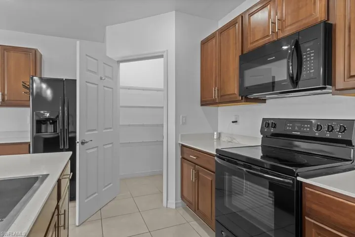 Kitchen with black appliances, sink, and light tile patterned flooring