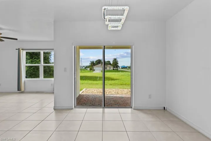 Empty room featuring plenty of natural light, light tile patterned floors, and ceiling fan