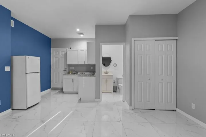 Kitchen featuring white fridge, white cabinetry, and sink