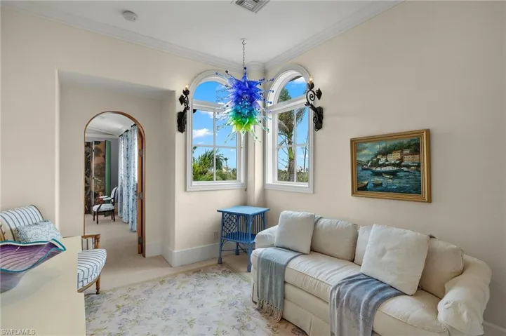 Carpeted living area featuring ornamental molding and arched walkways
