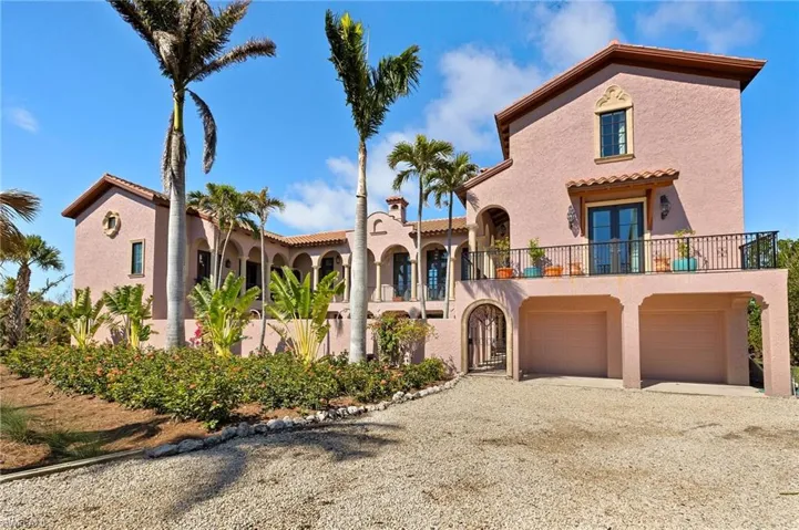 Mediterranean / spanish home with gravel driveway, stucco siding, a balcony, french doors, and a tile roof