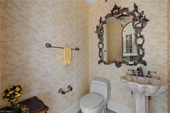Half bathroom with baseboards and wallpapered walls
