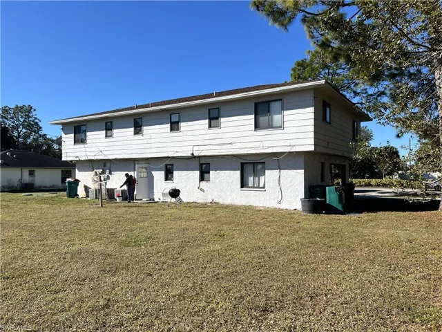 Rear view of house featuring a yard and stucco siding