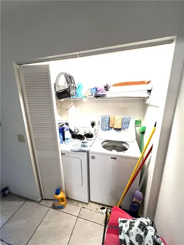 Washroom featuring light tile patterned floors and washer and clothes dryer
