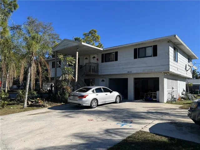 View of front facade featuring concrete driveway, a garage, a balcony, and stairway