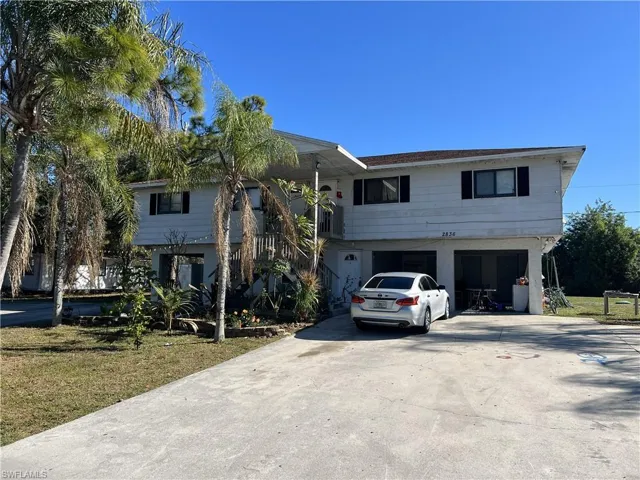 View of front of home with driveway, stairway, an attached garage, and a front yard