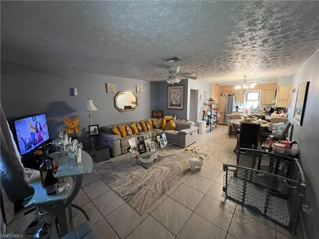 Living room featuring tile patterned flooring, a chandelier, and a ceiling fan