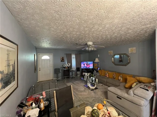 Living area with a ceiling fan and a textured ceiling