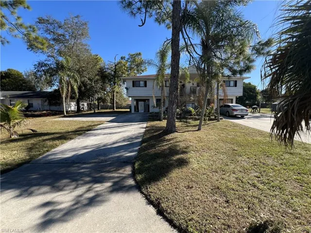 Raised beach house featuring concrete driveway and a front lawn