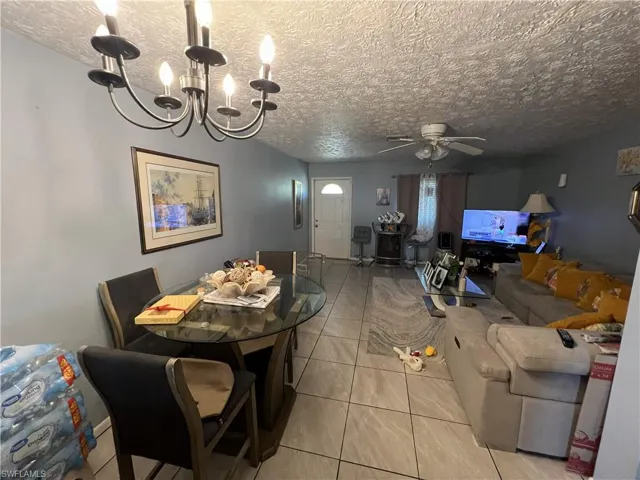 Dining room with ceiling fan, light tile patterned floors, a textured ceiling, and a chandelier