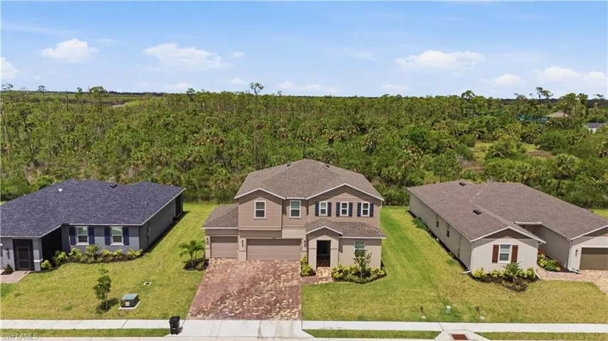 Two-story residence featuring a neutral-toned exterior, dark shingle roof, and a paver driveway