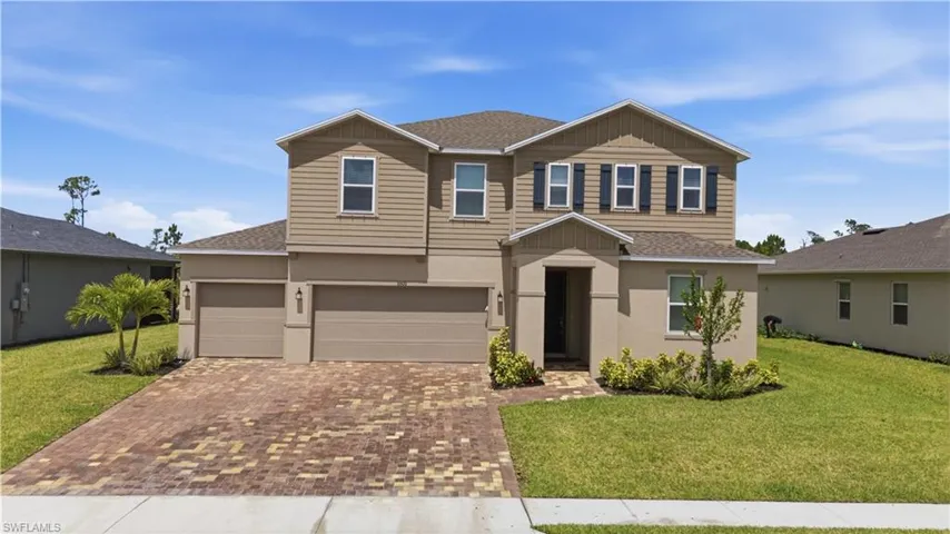 Two-story residence featuring a three-car garage, paver driveway, and a covered entry