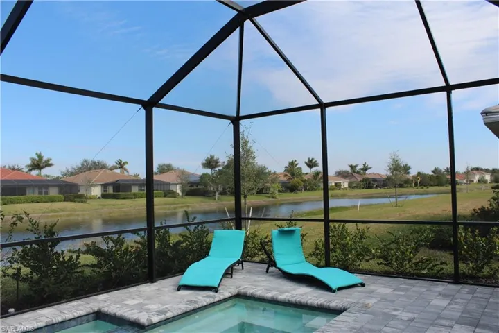 View of swimming pool with a lanai, a hot tub, a water view, and a patio