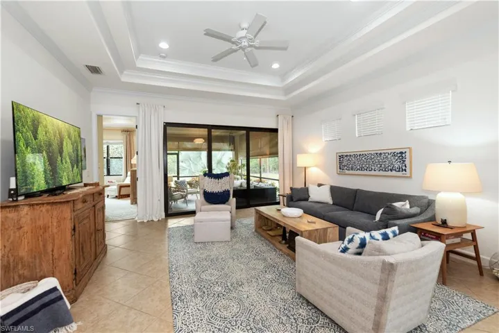 Living area with plenty of natural light, crown molding, a tray ceiling, recessed lighting, and light tile  flooring
