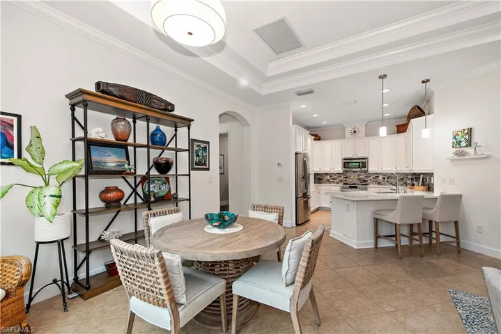 Dining area with arched walkways, light tile patterned floors, crown molding, and recessed lighting