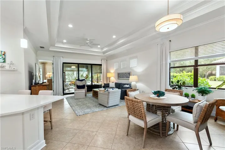 Dining area featuring ornamental molding, a raised ceiling, recessed lighting, light tile patterned floors, and a ceiling fan