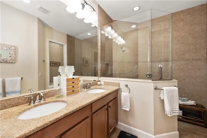 Bathroom featuring double vanity, walk in shower, and recessed lighting