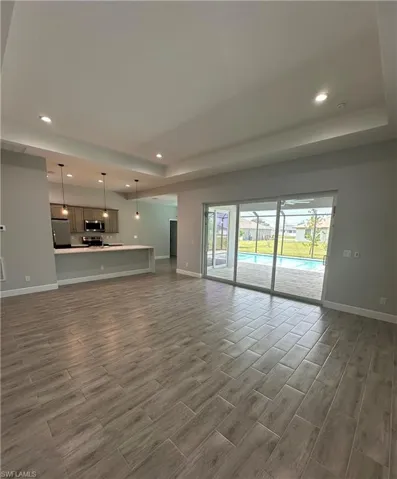 Unfurnished living room with a raised ceiling, recessed lighting, and wood tiled floors
