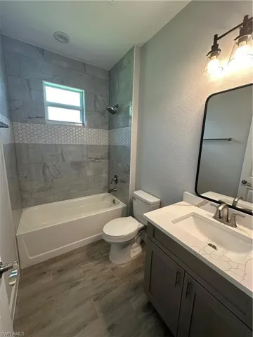 Full bath featuring a textured wall, vanity, and bathtub / shower combination