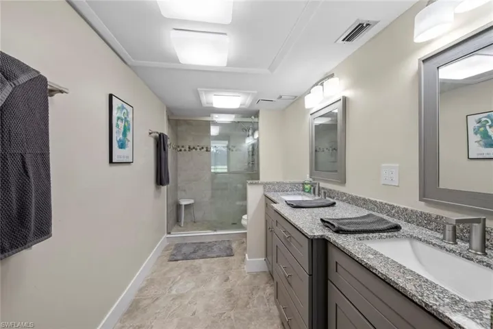 primary bathroom with vanity with extensive cabinet space, dual sinks, toilet, a shower with shower door, and tile flooring