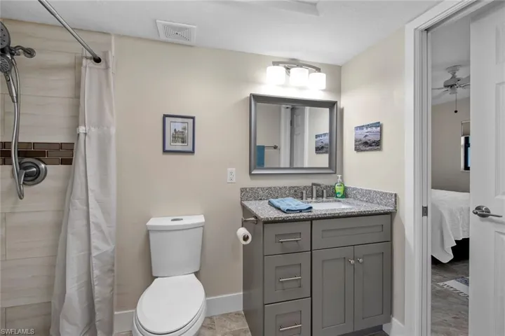 Bathroom featuring tile flooring, vanity, toilet, and ceiling fan