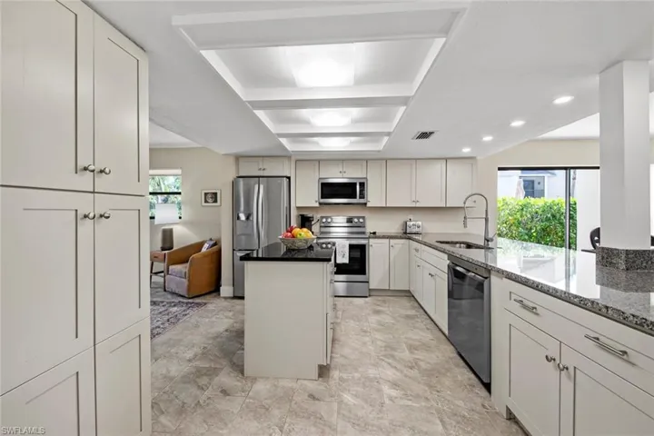 Kitchen with white cabinetry, stainless steel appliances, sink, and light tile floors