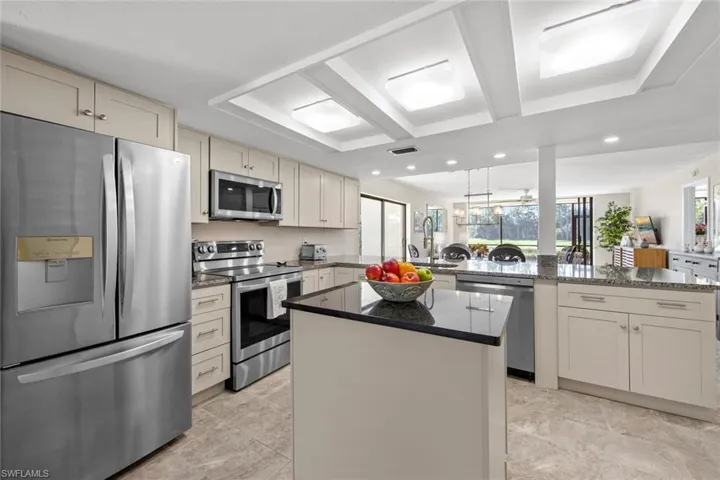 Kitchen featuring a kitchen island, dark stone countertops, appliances with stainless steel finishes, sink, and light tile floors
