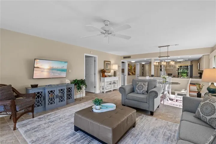 Tiled living room featuring ceiling fan with notable chandelier